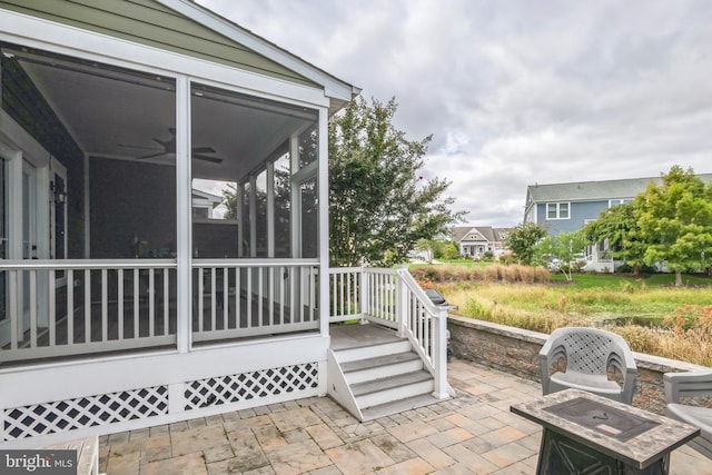 view of patio with ceiling fan and a sunroom