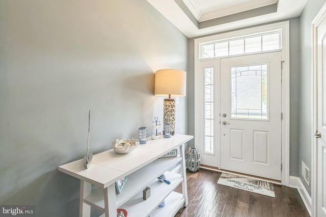 foyer with ornamental molding, a tray ceiling, and dark hardwood / wood-style flooring