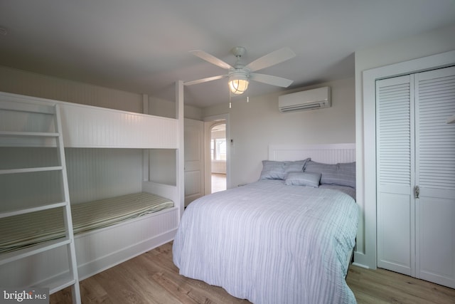 bedroom with ceiling fan, a closet, light wood-type flooring, and a wall mounted air conditioner