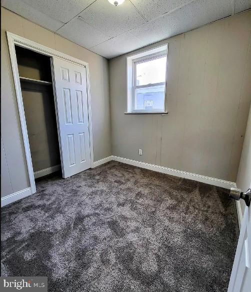 unfurnished bedroom featuring dark carpet and a closet