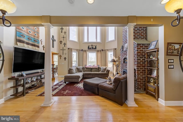 living room with decorative columns, light hardwood / wood-style floors, and a fireplace