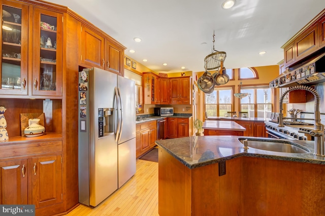 kitchen featuring dark stone counters, stainless steel refrigerator with ice dispenser, light hardwood / wood-style floors, and kitchen peninsula