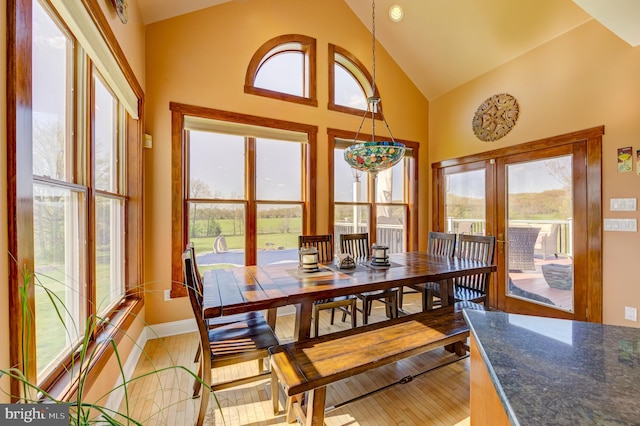 dining space featuring light hardwood / wood-style flooring, high vaulted ceiling, plenty of natural light, and french doors