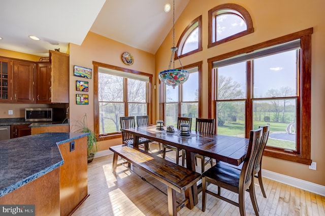 dining area featuring light hardwood / wood-style floors and high vaulted ceiling