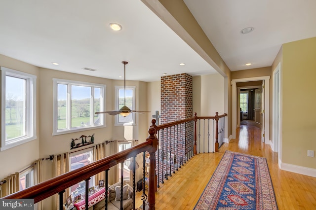 hallway with a healthy amount of sunlight and light hardwood / wood-style flooring