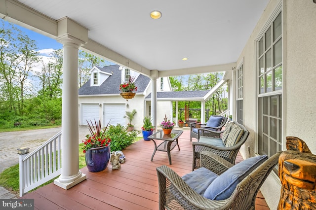 wooden terrace featuring covered porch and a garage