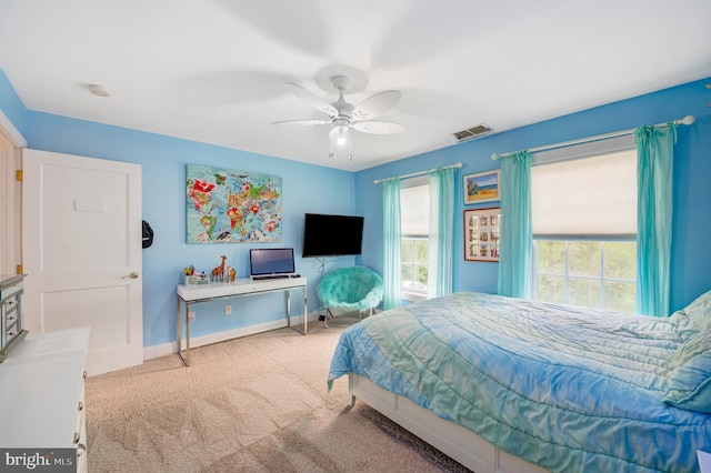 carpeted bedroom featuring multiple windows and ceiling fan