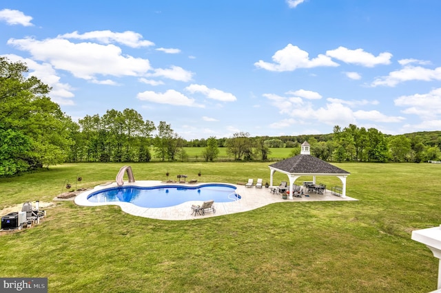 view of pool featuring a lawn, a gazebo, a water slide, and a patio area