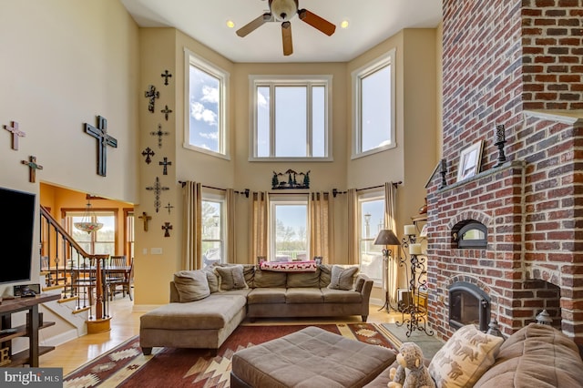 living room featuring ceiling fan, light hardwood / wood-style floors, and a high ceiling