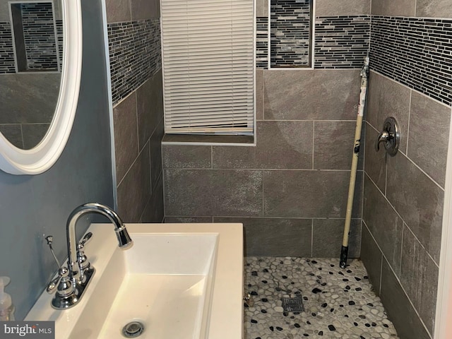 bathroom featuring a tile shower, tile patterned flooring, and sink