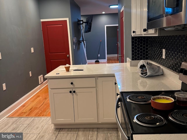 kitchen featuring white cabinets, backsplash, stainless steel appliances, light stone countertops, and light hardwood / wood-style floors