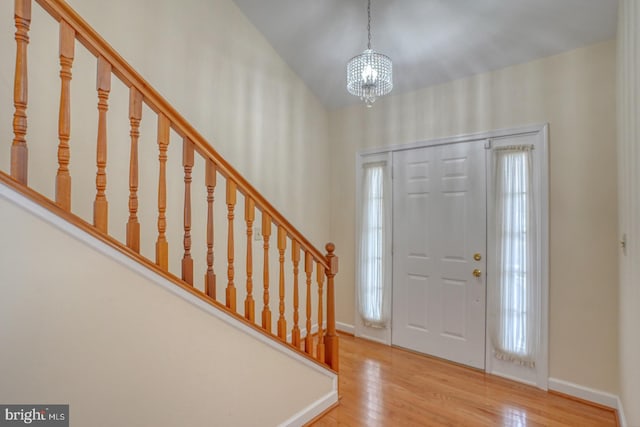 entrance foyer featuring wood-type flooring, lofted ceiling, and a notable chandelier