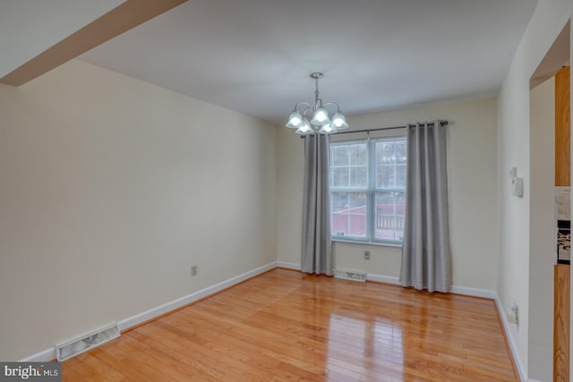 unfurnished dining area featuring a notable chandelier and light wood-type flooring