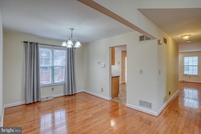 unfurnished room featuring light hardwood / wood-style flooring and an inviting chandelier