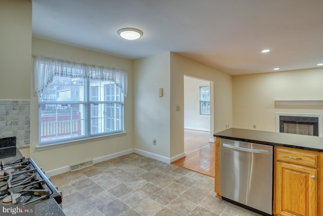 kitchen with tasteful backsplash, a wealth of natural light, dishwasher, and gas range oven