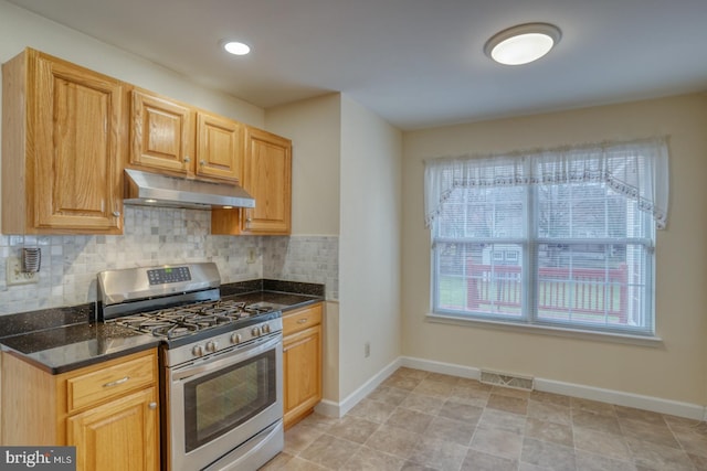 kitchen featuring tasteful backsplash, dark stone countertops, stainless steel range with gas cooktop, and light tile patterned flooring