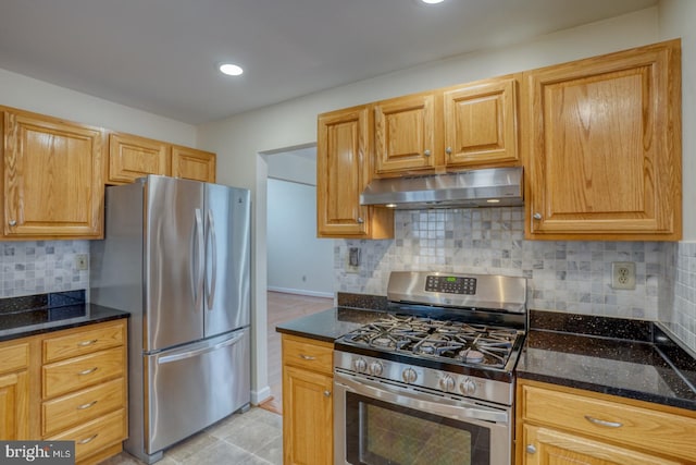 kitchen with dark stone countertops, decorative backsplash, light tile patterned floors, and stainless steel appliances