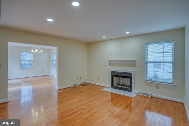 unfurnished living room with light hardwood / wood-style flooring and a chandelier