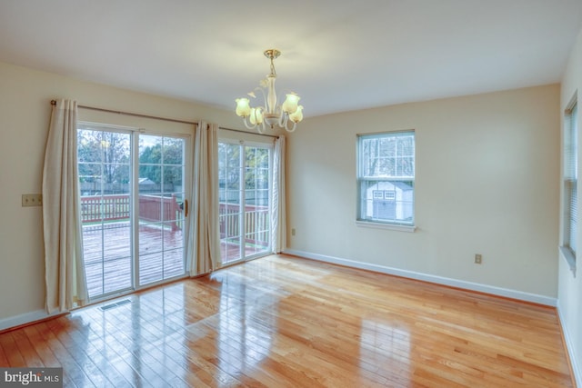 empty room with light hardwood / wood-style flooring and an inviting chandelier