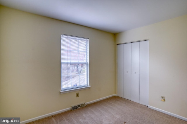 unfurnished bedroom featuring light colored carpet and a closet