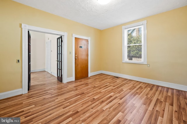 unfurnished room with light hardwood / wood-style floors and a textured ceiling