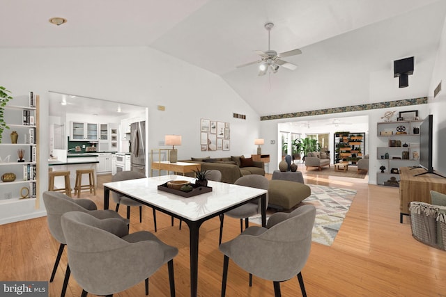 dining room featuring light hardwood / wood-style flooring, ceiling fan, and high vaulted ceiling