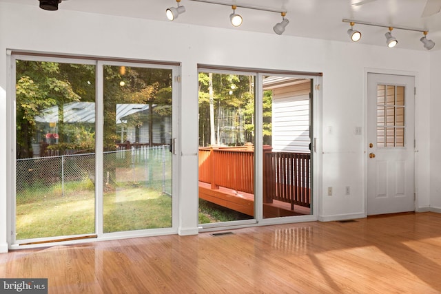 doorway with hardwood / wood-style floors and rail lighting