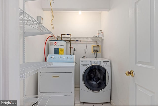 clothes washing area featuring electric water heater, separate washer and dryer, and light tile patterned floors