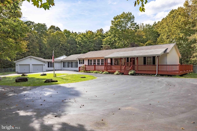 ranch-style house with a front lawn, an outdoor structure, a deck, and a garage