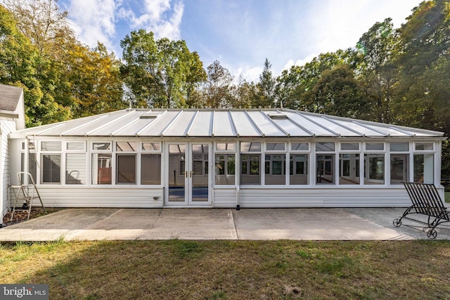 rear view of house with a sunroom, a patio, and a lawn