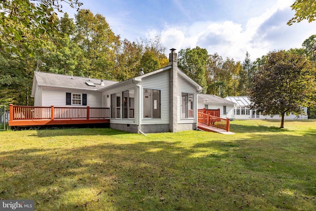 back of property with a deck and a yard