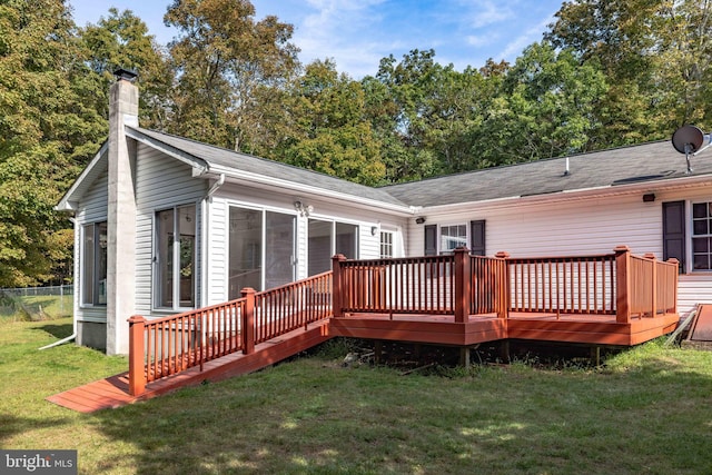 back of property featuring a wooden deck and a lawn