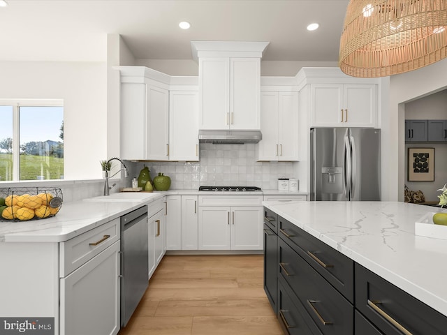 kitchen featuring appliances with stainless steel finishes, white cabinetry, sink, backsplash, and hanging light fixtures