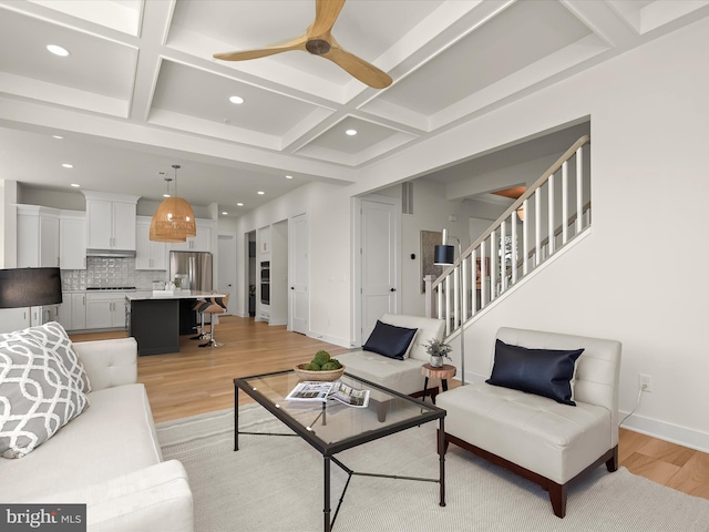 living room with coffered ceiling, beam ceiling, ceiling fan, and light wood-type flooring