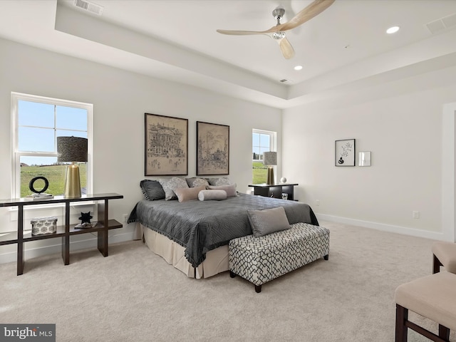 bedroom featuring light colored carpet, ceiling fan, and a tray ceiling