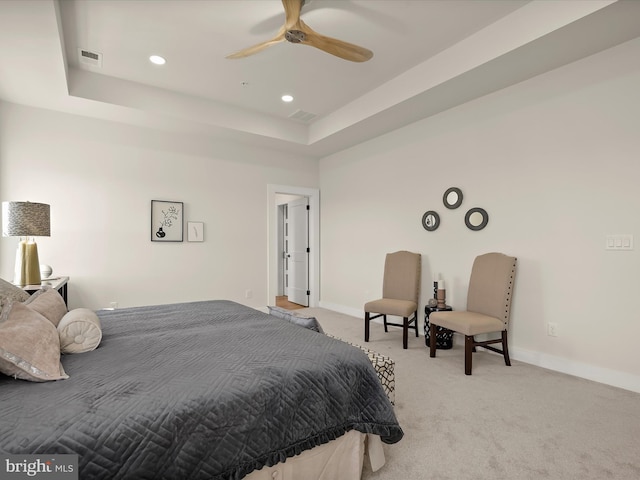 bedroom featuring ceiling fan, a tray ceiling, and light carpet