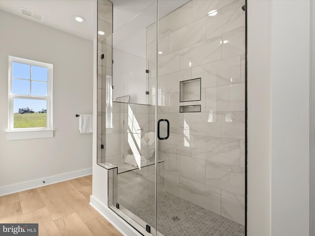 bathroom with hardwood / wood-style flooring and a shower with shower door