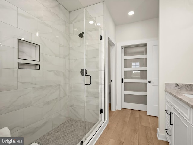 bathroom with an enclosed shower, vanity, and wood-type flooring