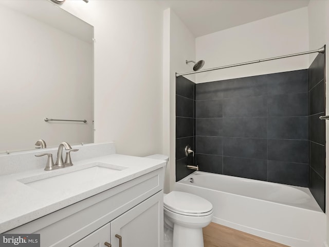 full bathroom with vanity, hardwood / wood-style floors, tiled shower / bath combo, and toilet