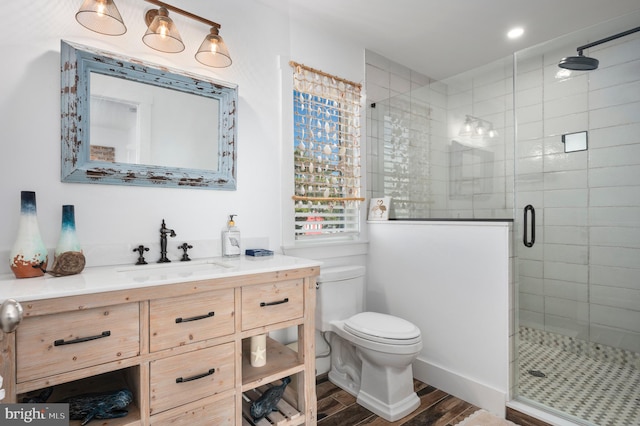 bathroom featuring toilet, hardwood / wood-style floors, a shower with shower door, and vanity