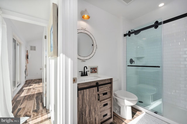 bathroom with vanity, hardwood / wood-style floors, walk in shower, and toilet