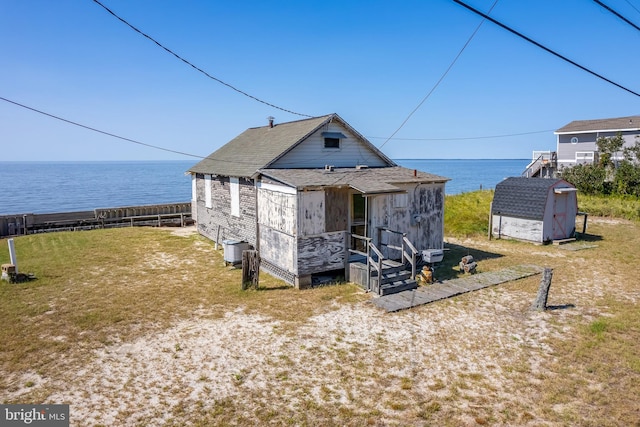 view of front of house featuring a water view, a storage unit, and a front yard