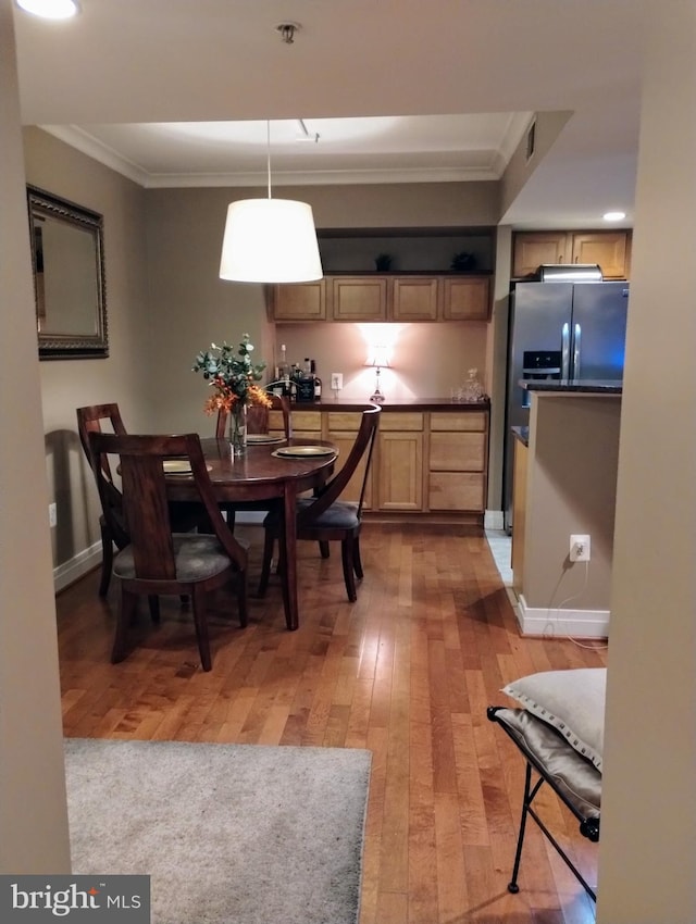 dining space with light wood-type flooring and crown molding