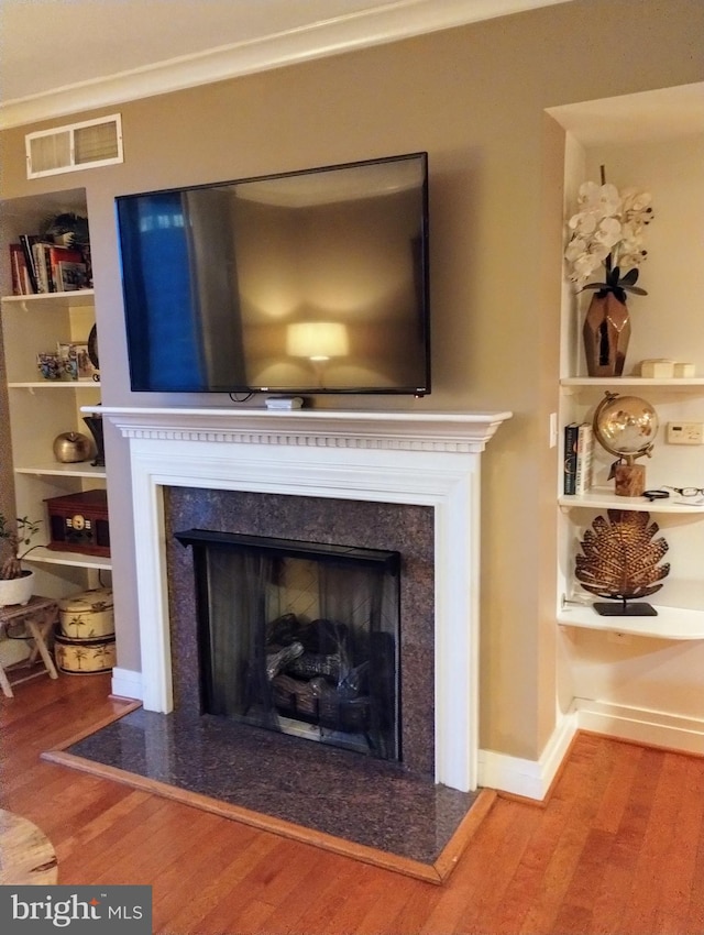 room details with hardwood / wood-style flooring, crown molding, and a high end fireplace