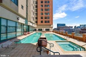 view of pool with a hot tub and a patio