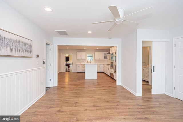 interior space featuring ceiling fan, stainless steel double oven, and light hardwood / wood-style floors