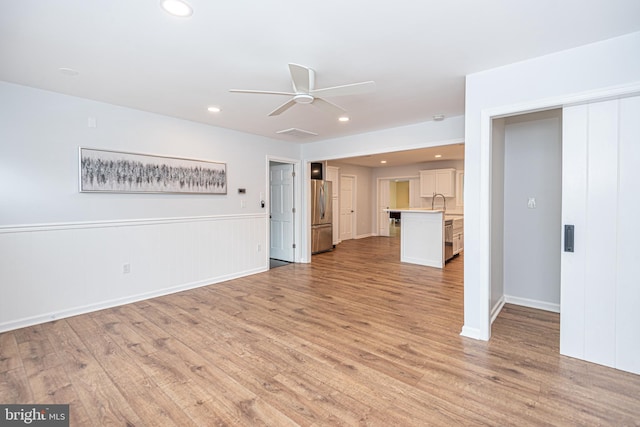 unfurnished living room with light wood-type flooring and ceiling fan