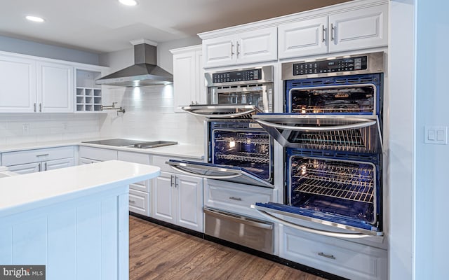 kitchen with black stovetop, white cabinets, wall chimney exhaust hood, and dark wood-type flooring