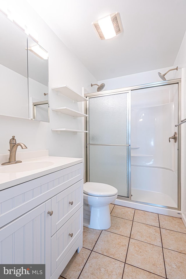 bathroom featuring a shower with door, toilet, vanity, and tile patterned floors