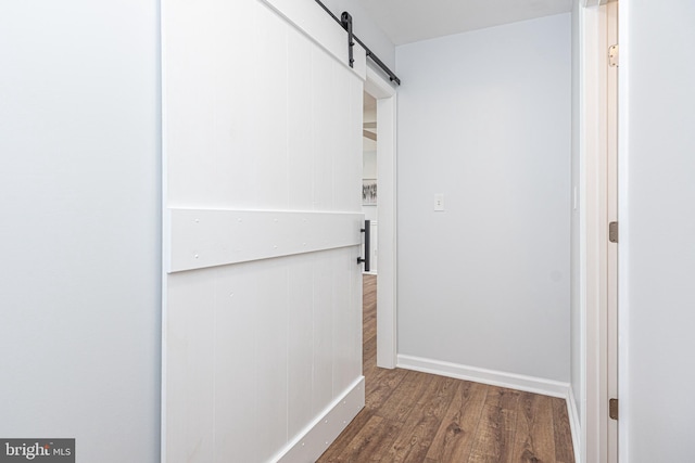 corridor with a barn door and hardwood / wood-style floors